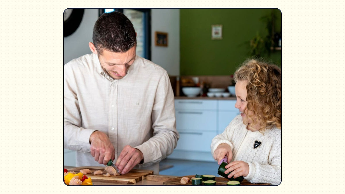 Un papa et sa fille coupent ensemble, chacun sur sa planche : lui le poulet, elle la courgette.