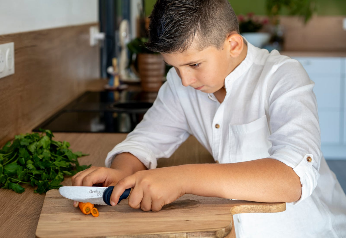 Un garçon concentré coupe des carottes avec son Genius Cut